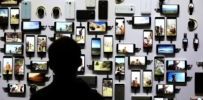 Un visitante de una feria tecnológica mira toda la gama de dispositivos de una conocida marca. Justin Sullivan. AFP.